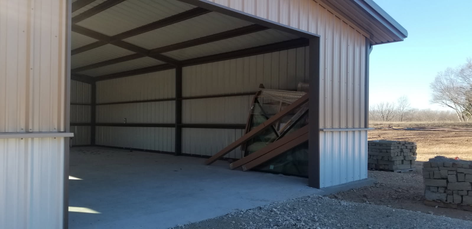 Small metal barndominium with open bay door in rural Central Texas setting